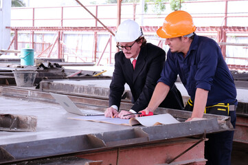 Engineer in safety helmet holding laptop working in industrial factory.