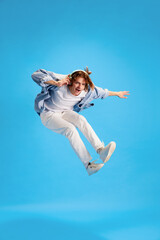 Full-length portrait of young man, dressed fashion casual outfit and jumps with joy and joy listening to music in modern headphones. Concept of self-expression, human emotions, retro music and party.