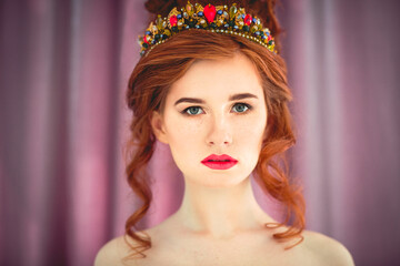 Beautiful redhaired fashion model posing in evening dress and in the diadem