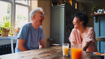 Joyful senior couple laughing over drinks in cozy home kitchen, candid moment of happiness.