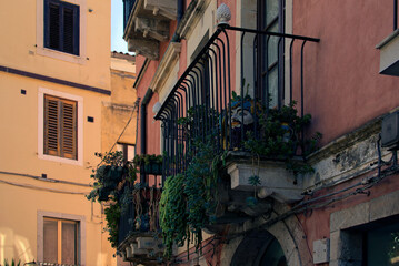 Ancient house with beautiful authentic decorated balconies with blooming potted flowers, succulents and cacti. Traditional view of the building in medieval Taormina. Travel and tourism concept