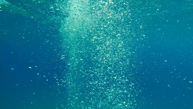 Air bubbles from the scuba divers rise to surface of water, Slow motion. Natural background, bubbles flowing up in turquoise water. Air bubbles floating from sea botton to water surface