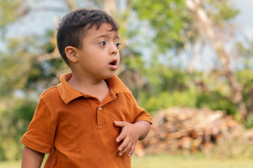 A curious child with Down syndrome lost in thought in a rustic countryside setting