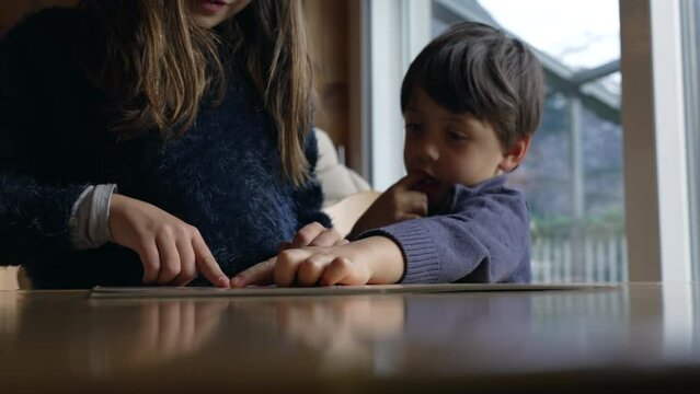 Young Siblings at Diner Deciding What to Eat, Child's Hand on Menu