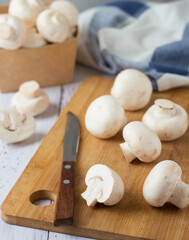 Champignons on a cutting board, knife, kitchen towel. Cooking process, cutting mushrooms.