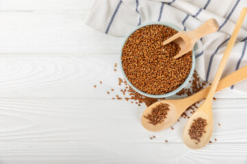 Buckwheat porridge in a bowl on a white wooden background. Healthy food. Diet. Organic cereal.
 Raw buckwheat. gluten free ancient grain for healthy diet. Place for text. Copy space.