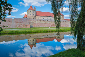 Medieval fortress reflecting in water, summer landscape