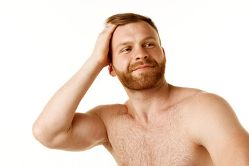 Fototapeta premium Portrait of athlete young man with bare shoulders run your hand through his red hair, after cutting it against white studio background. Concept of natural beauty, spa treatment, selfcare, cosmetic. Ad