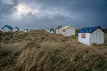 Fototapeta na wymiar Gouville, France - 12 30 2023: View of colorful bathing wooden cabins of Gouville on the dunes.