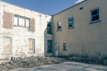 Facade of light brick buildings intersecting, derelict, boarded up and broken windows, urban decay, squalor, ghetto, nobody