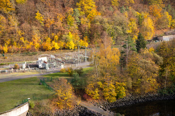 Fototapeta na wymiar Substation between autumnal trees and a River