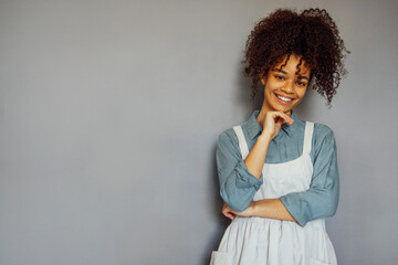 Young black woman wearing beige apron isolated on grey background with copy space.