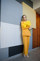 A woman wearing a yellow suit while holding flowers. 4628