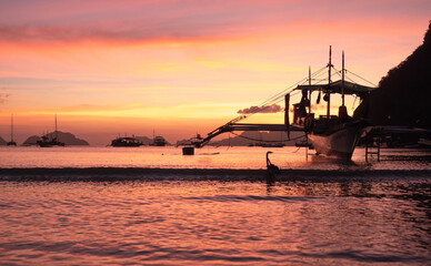 Traditional philippine boat bangka at sunset time. Beautiful sunset with silhouettes of philippine...
