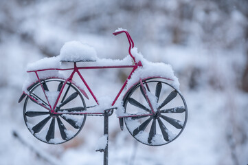 Eingeschneites rotes Windrad in Fahrradform vor unscharfem Hintergrund