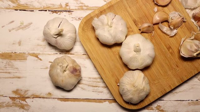 Ripe garlic cloves in bamboo plate. Unpeeled garlic, raw food from nature.