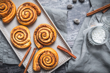 Homemade cinnamon rolls on a gray earthenware tray on gray background