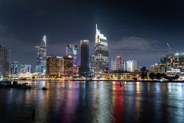 Fototapeta na wymiar Ho Chi Minh City skyline and the Saigon River. Amazing colorful night view of skyscraper and other modern buildings at downtown. Travel concept