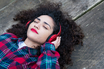 Young woman listening to music and studying outdoors with her computer and mobile phone