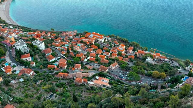 the orange roofs of verdant landscape of Roquebrune-Cap-Martin, houses along coast in the south of France at sunset, view from the Luxury Mediterranean Hotel on the mountain, empty beach, azure water