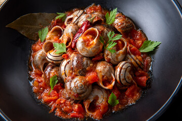Piatto di lumache condite con sugo piccante, tradizionale ricetta della cucina sarda, cibo italiano 