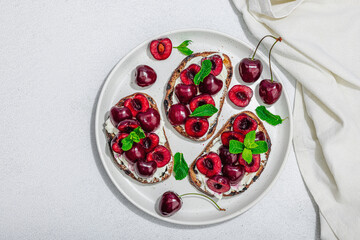 Fresh bread sandwiches with sweet cherry, cream cheese and mint leaves. Morning breakfast concept