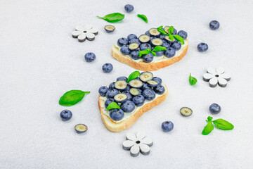 Fresh bread sandwiches with sweet blueberries, cream cheese and basil leaves. Good morning concept