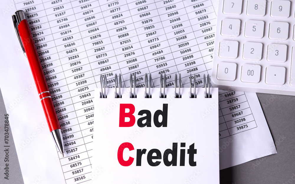 Poster bad credit text on notebook with pen, calculator and chart on grey background