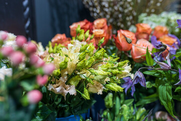 A variety of colors is near the flower shop. Large bouquets in tin vases.