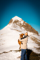 woman with her dog in her arms kissing him. at the top of a snowy and frozen mountain. peak Arlas