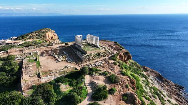 Aerial drone video of iconic archaeological site of Cape Sounio and famous Temple of Poseidon built uphill overlooking Aegean sea, Attica, Greece