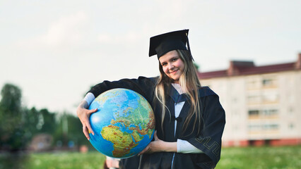 A graduate student poses with a globe in front of her friends.