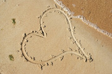 Love and feelings. A heart drawn on wet sand
