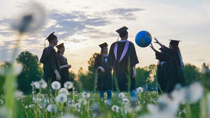 Graduates in costume playing with a ball at sunset.