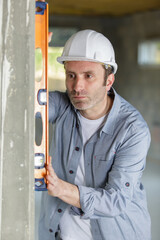 mature worker using spirit level on a concrete wall