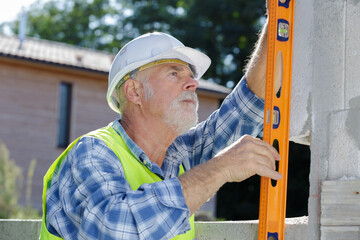 a mature builder holding a level