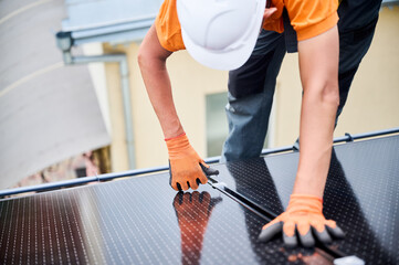 Worker building photovoltaic solar panel system on rooftop of house. Man engineer in helmets and...