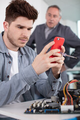 boss is annoyed because young worker is on his smartphone