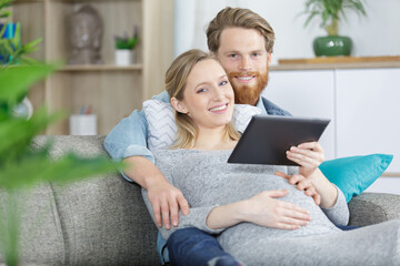 handsome husband and pregnant woman playing tablet computer