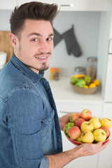 Fototapeta premium young man holding a bowl of fruit