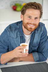 smiling beared man holding cup of coffee