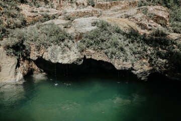 Water dripping from a rock surrounded by green moss walls. Beautiful tropical background at the waterfall. Moss texture with blurred background. Weeping rocks. Beauty and energy