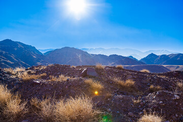 rocks and dry grass tufts in autumn mountains backlit scene at sunny day.