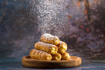 Delicious puff pastry tubes filled with custard. Powdered Sugar - obrazy, fototapety, plakaty