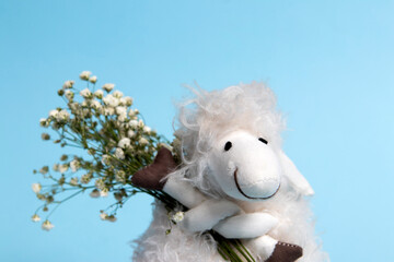 A cute sheep toy holding white flowers on a blue background