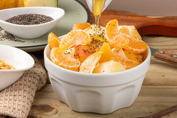 Dropping delicious honey in fruit salad. Selective focus.