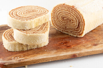 Sliced roll cake on cutting board isolated on white background.
