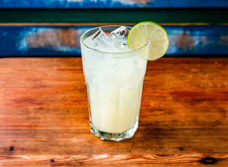 served in glass topping with lemon slice and ice cube isolated on wooden table side view of hong kong drink