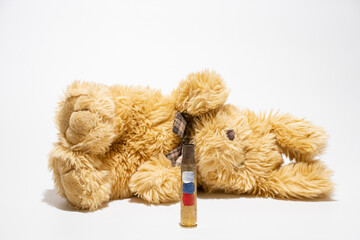 Empty cartridge case with a painted Russian flag and in the background a plush soft toy for children on a white background, war
