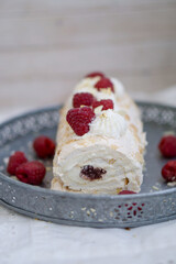 Homemade Mringue Pavlova roll cake with whipped cream and fresh raspberries on top close up selective focus